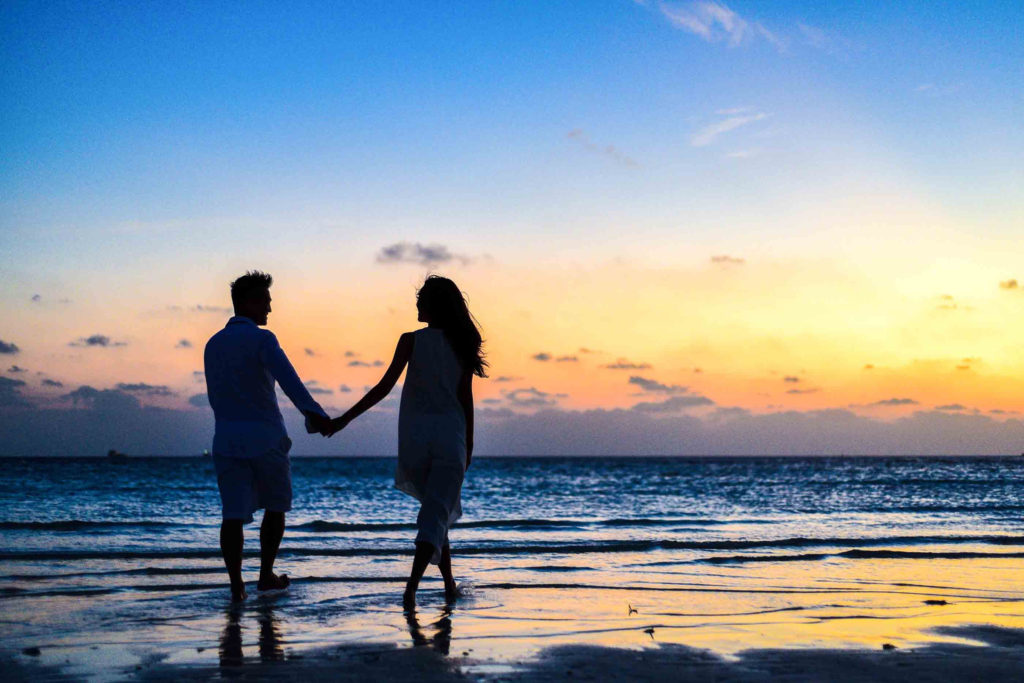 Couple holding hands on a beach.